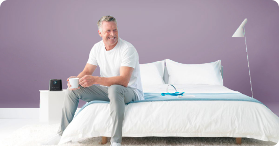 A well-rested man sitting happily on his bed