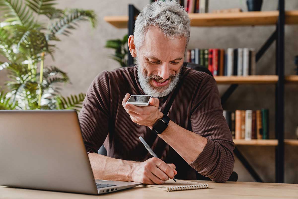 Man on computer while writing notes