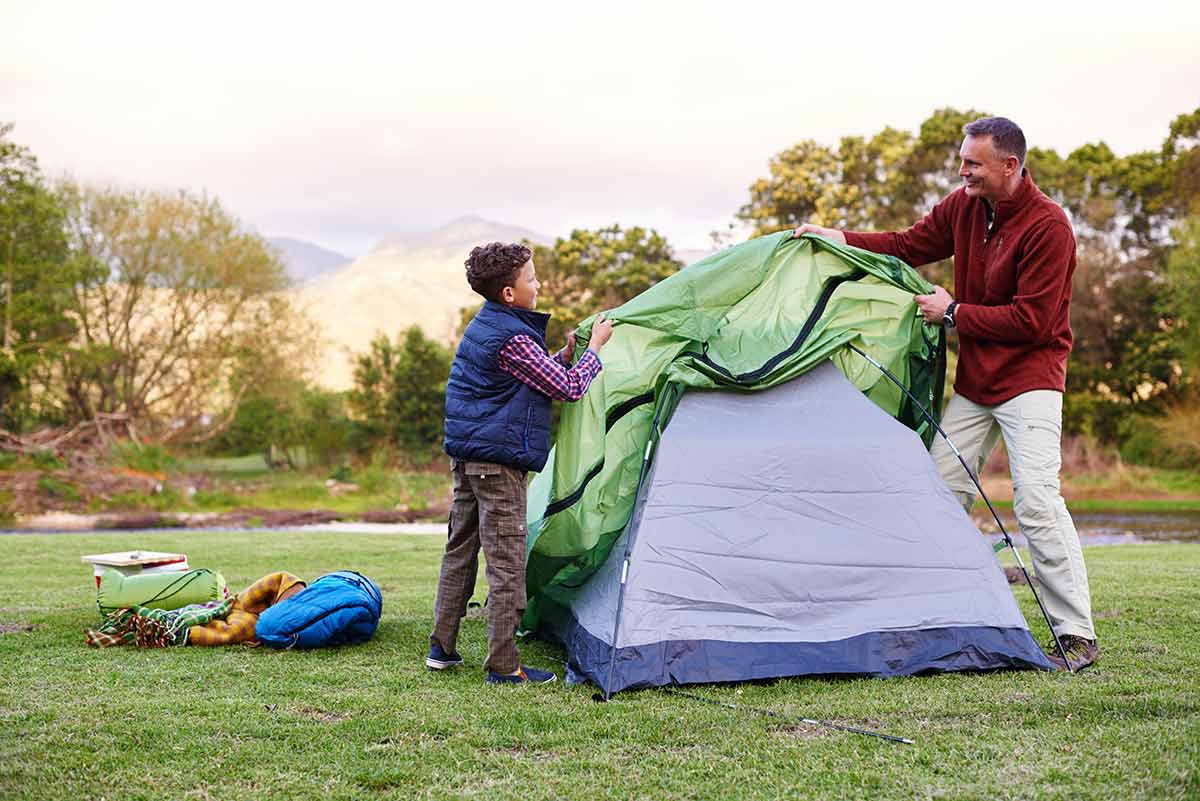 Father and son setting up a tent outside